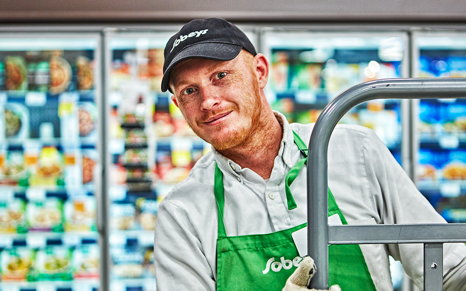 Male Sobeys employee stocking frozen food section.