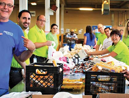 A group of FreshCo employees packing food into milk crates.