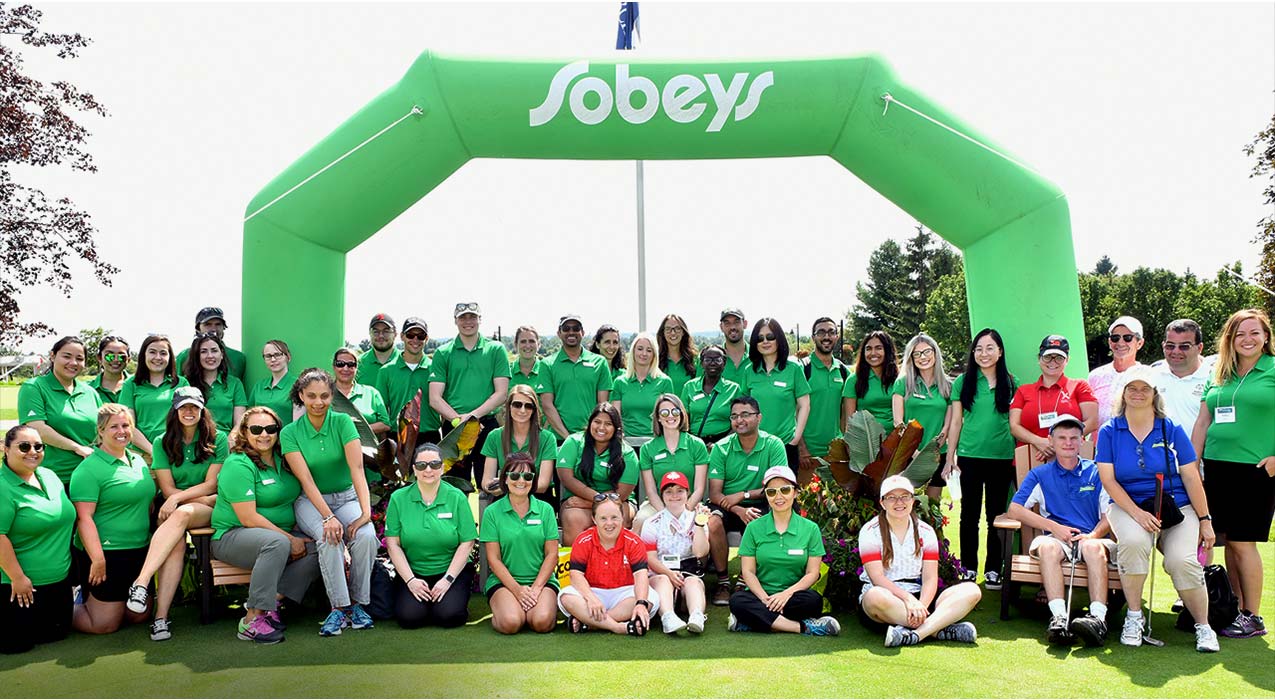 A group of Sobeys employees wearing green shirts on a golf course.