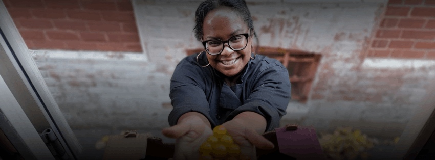 An image of a woman carrying something in her hand with a smiling face.